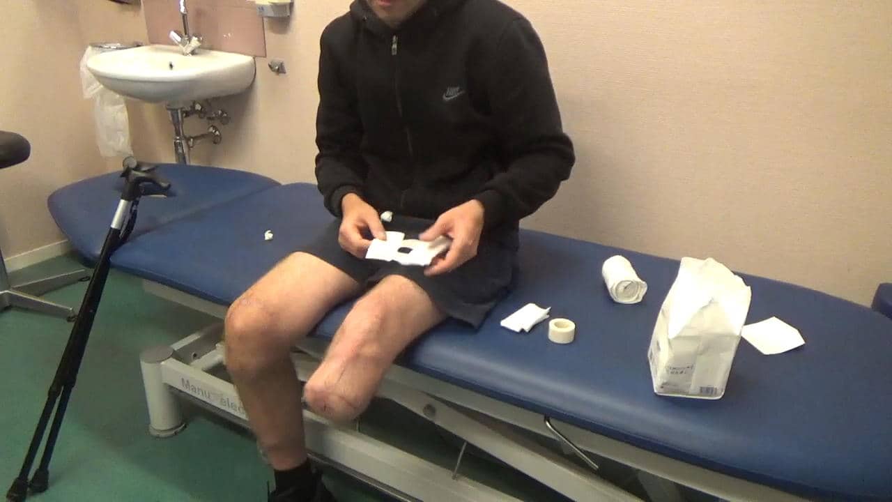 Man zit op doktersbed met tape in hand.