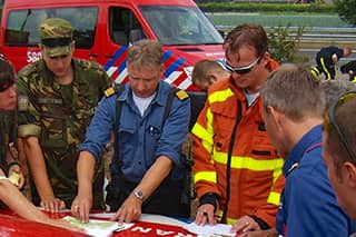 A member of the military examines a map of the nature reserve together with members of the fire service.
