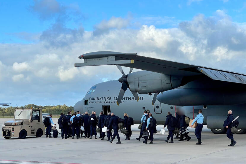 Military personnel enters an airplane.