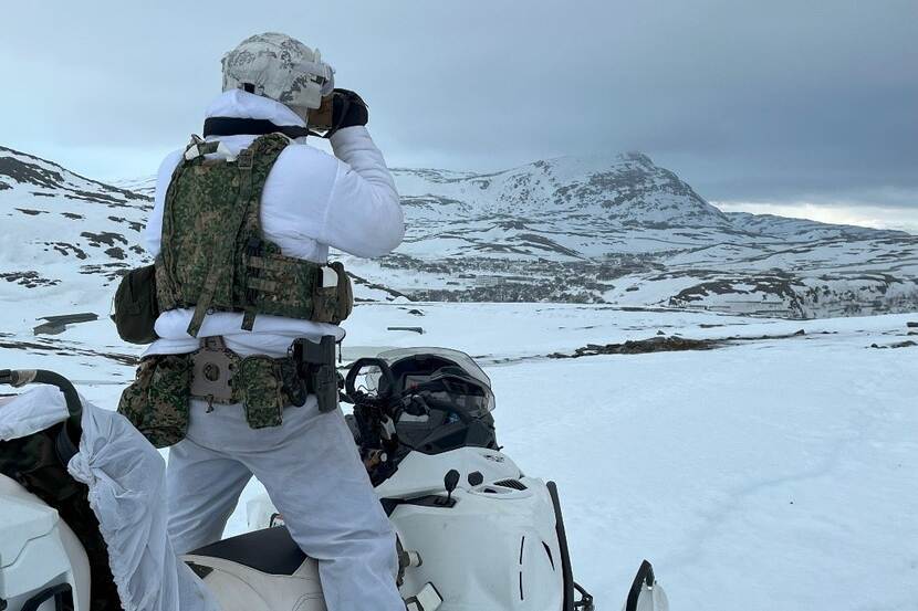 A marine scans the surroundings with binoculars during Nordic Response.