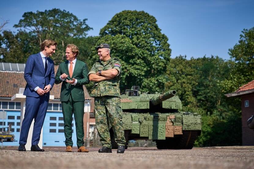 The Minister,  State Secretary and Commander are standing in front of a tank.