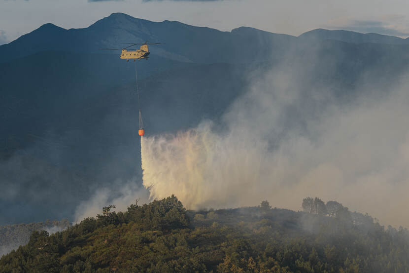 Chinook-transporthelicopter dumps water on a forest fire in Spain