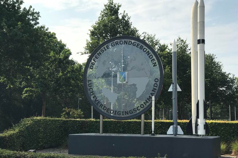Ingang kazerne met groot rond bord met logo en tekst Def