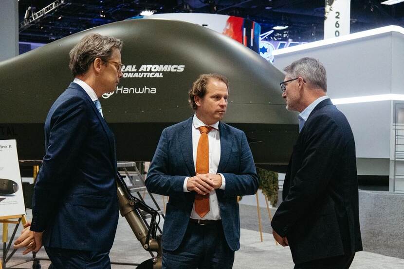 State Secretary Tuinman in conversation with 2 men.