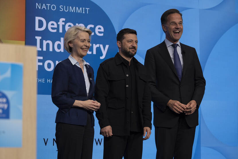 A woman and two men are standing next to each other on stage, laughing.
