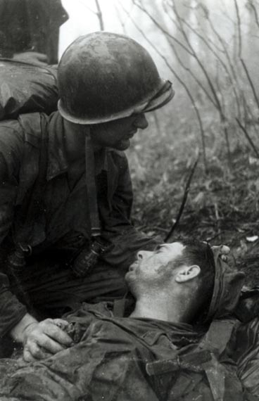 A Dutch soldier stays close to a dying comrade during the fighting on Hill 975 in May 1951.