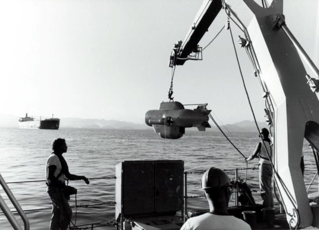 In 1987, HNLMS Hellevoetsluis slowly lowers a PAP, a small unmanned submarine, into the water to carry out mine detection work in the harbour of Fuyairah.