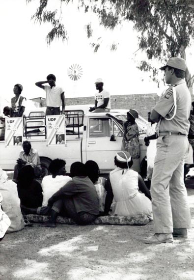 In the run-up to the November 1989 Namibian elections, Dutch UNTAG monitors keep an eye on a meeting held by the United Democratic Front (UDF) in the Kalahari desert on the border with Botswana.