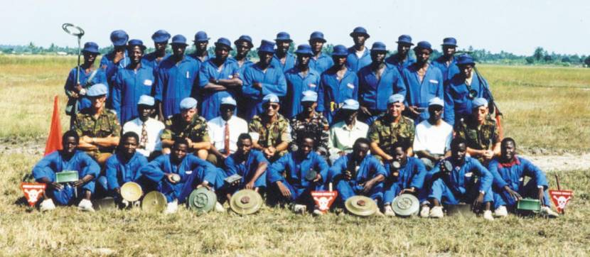 Instructors with their Mozambican trainees in April 1994. The trainees have various types of landmines at their feet, while 1 trainee (top left) shows a mine detector.