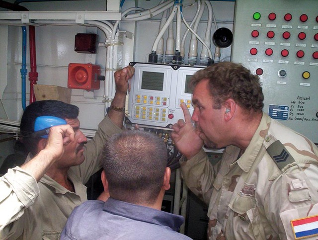 Sergeant Ron ten Boom explains security procedures to 2 members of the Iraqi Coast Defence Force in the engine room of a patrol vessel.