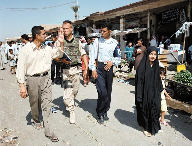 A Royal Netherlands Marechaussee officer supervises a colleague from the Iraqi police force during a patrol.