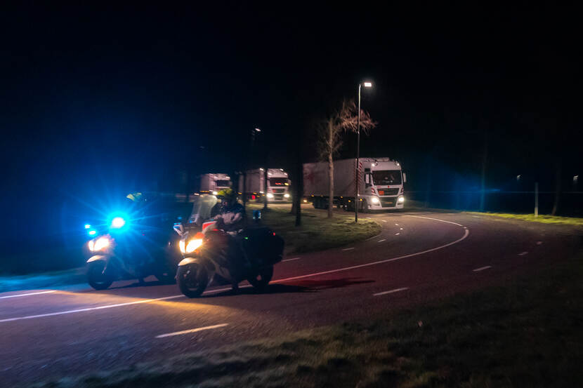 Militaire voertuigen met raketten en andere munitie 's nachts op weg naar Eindhoven. 2 marechaussees te motor rijden voorop.